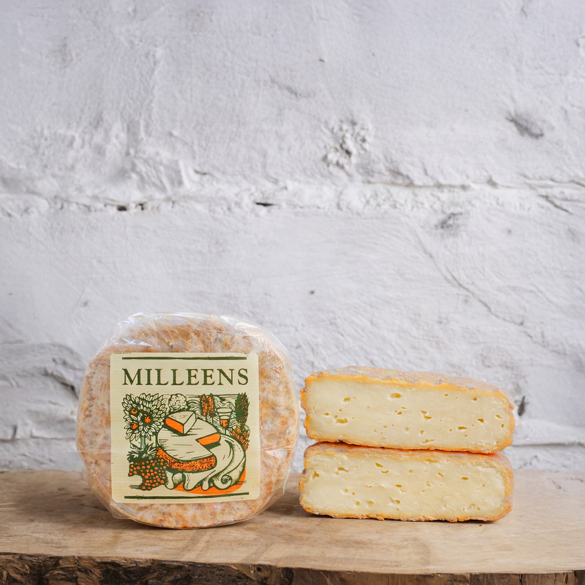 Two blocks of cheese with a Milleens label on a wooden surface against a textured white background
