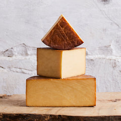 Three blocks of cheese stacked on a wooden surface with a marble background